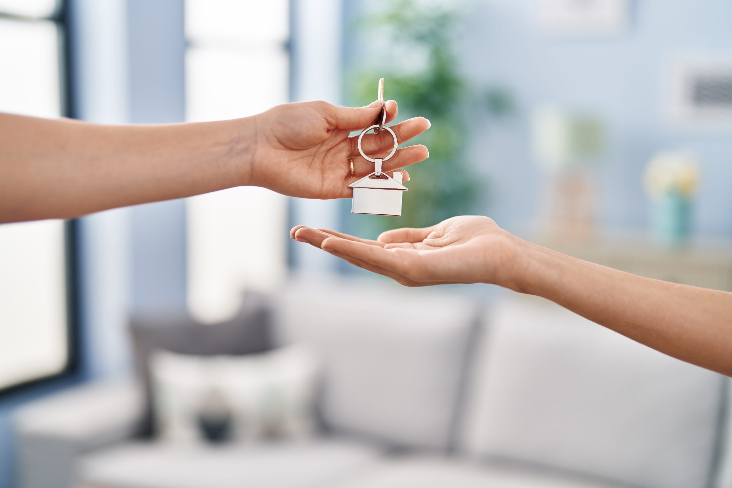 young woman holding key of new house at home, being given key
